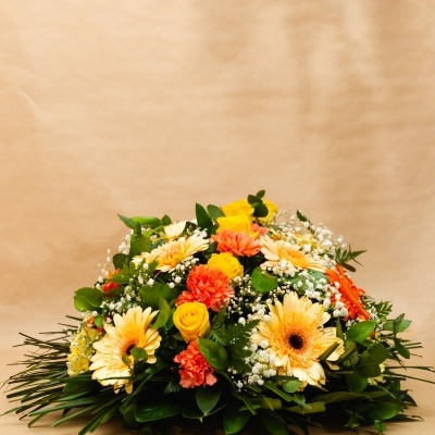 Arranjo floral com rosas amarelas, cravos laranja, margaridas creme e folhagem verde