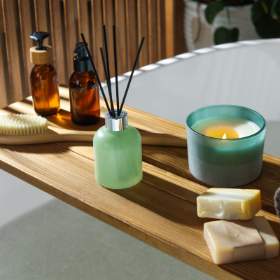 Prancha de madeira sobre banheira com vela, difusor, garrafas, escova e sabonetes