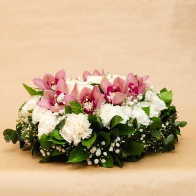 Arranjo floral branco e rosa com folhas verdes sobre fundo bege