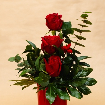 Arranjo de três rosas vermelhas com folhagens em vaso vermelho