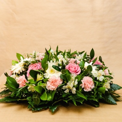 Arranjo floral com rosas cor-de-rosa, crisântemos brancos e folhagem verde.