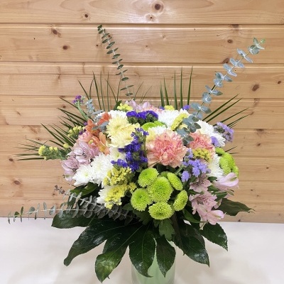 Arranjo floral colorido em vaso de vidro com fundo de madeira clara