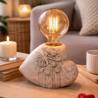 Lâmpada decorativa com base em forma de coração e rosas em relevo sobre mesa de madeira