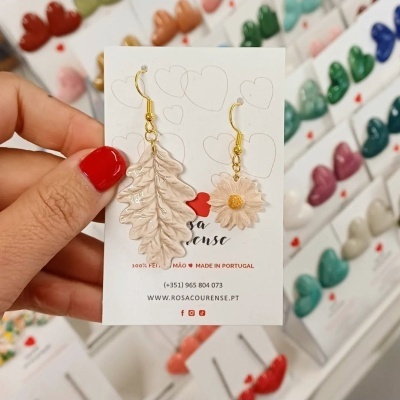 Brincos assimétricos creme em cartão branco com texto e logótipos coloridos ao fundo