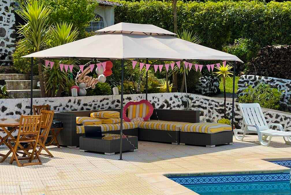 Zona exterior com pérgola, sofás modulares com almofadas amarelas e brancas, decoração cor de rosa e piscina