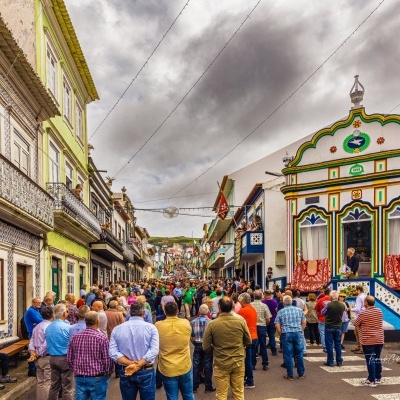 Rua antiga com pessoas e edifícios coloridos ao fundo sob céu nublado