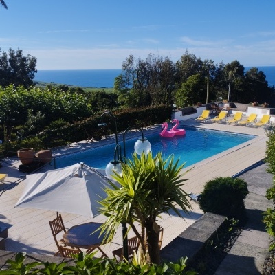 Piscina exterior com espreguiçadeiras amarelas e vista para o mar