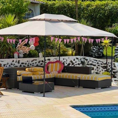 Zona exterior com pérgola, sofás modulares com almofadas amarelas e brancas, decoração cor de rosa e piscina