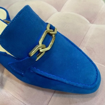 Mocassim feminino azul de veludo com corrente dourada sobre superfície almofadada rosa