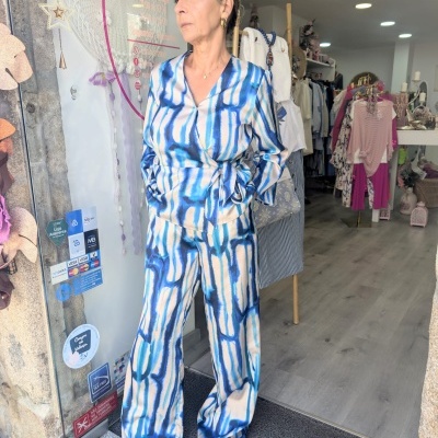 Mulher com macacão azul abstrato em frente à loja de roupa