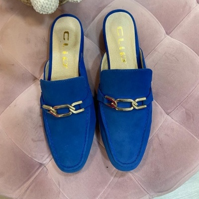 Mocassins azuis com corrente dourada sobre suporte estofado rosa claro