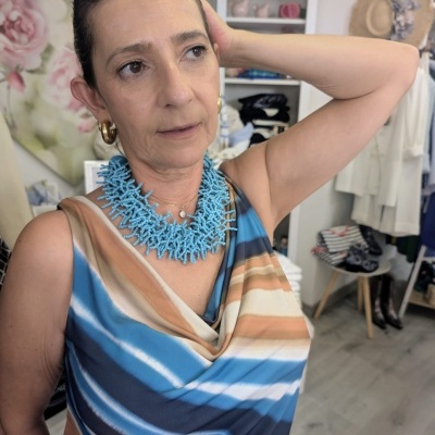 Mulher com vestido às riscas e colar azul em ambiente interno decorado