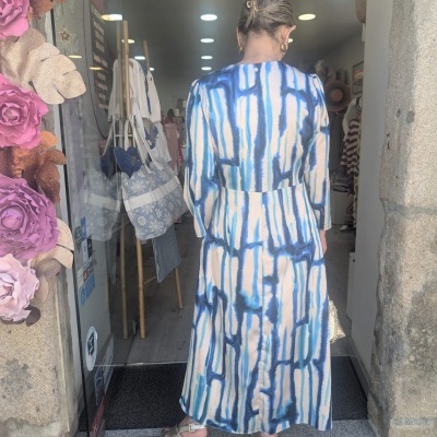 Mulher de costas com vestido azul e branco em entrada de loja