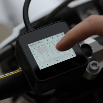 Ecrã táctil quadrado num guiador com interface técnica e dedo a tocar