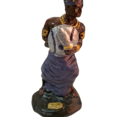 Estatueta de homem com saia roxa segurando cabeça de peixe