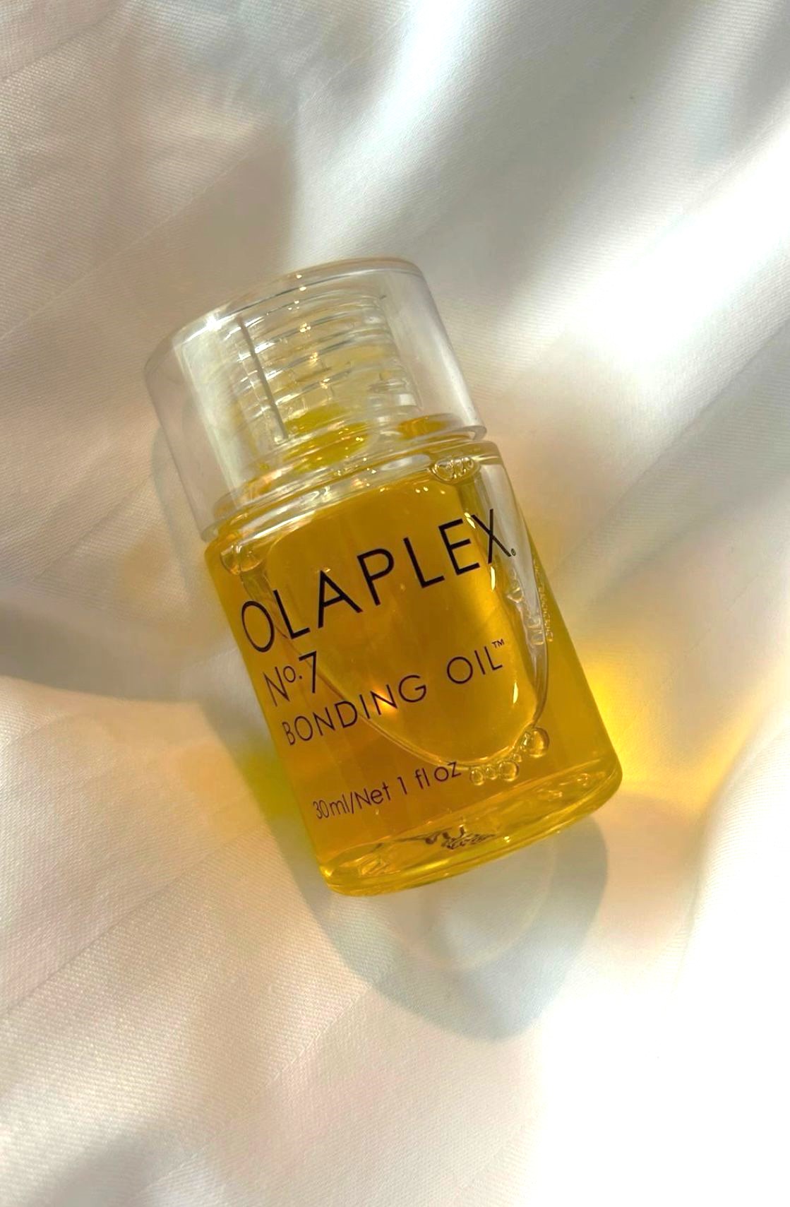 Olaplex Nº7 – Óleo Reparador, Fortalecedor e Protetor 30ml Frasco de óleo amarelo OLAPLEX sobre tecido branco