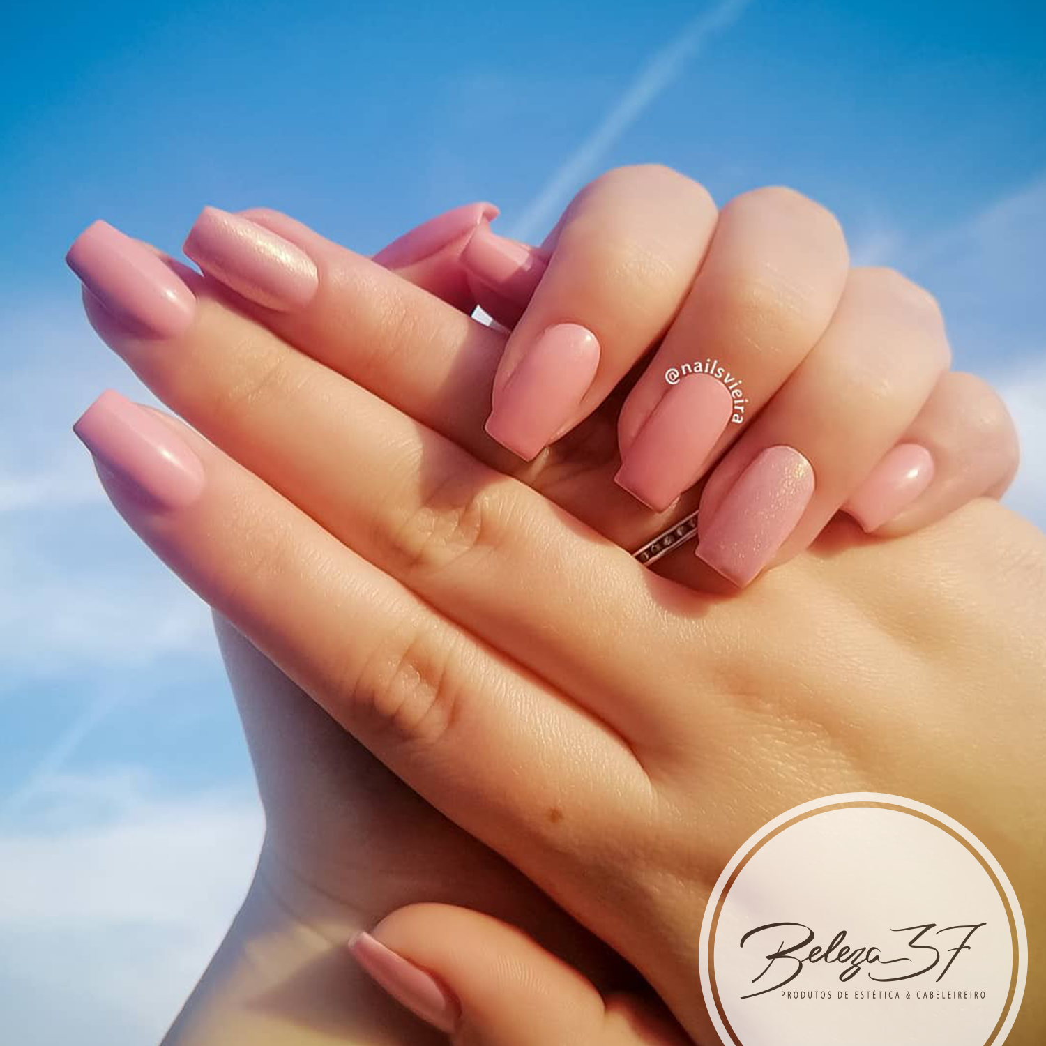 The Gel Polish Andreia G09 Mãos femininas com unhas rosa claro e céu azul ao fundo