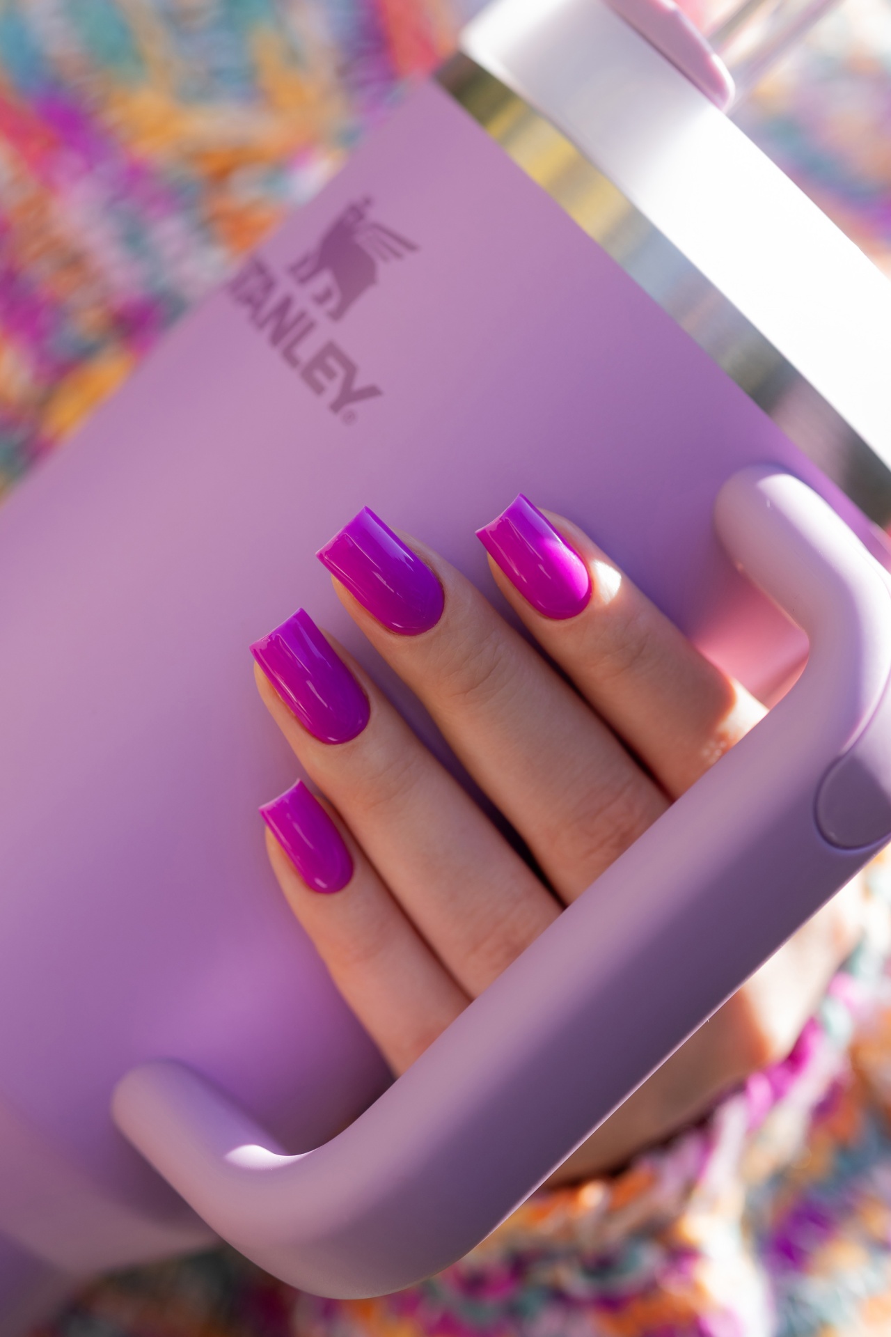 Verniz Gel Hot Pilates Club (Fúcsia‑Violeta Néon) Mão com unhas roxas segurando garrafa térmica lilás com logo Stanley