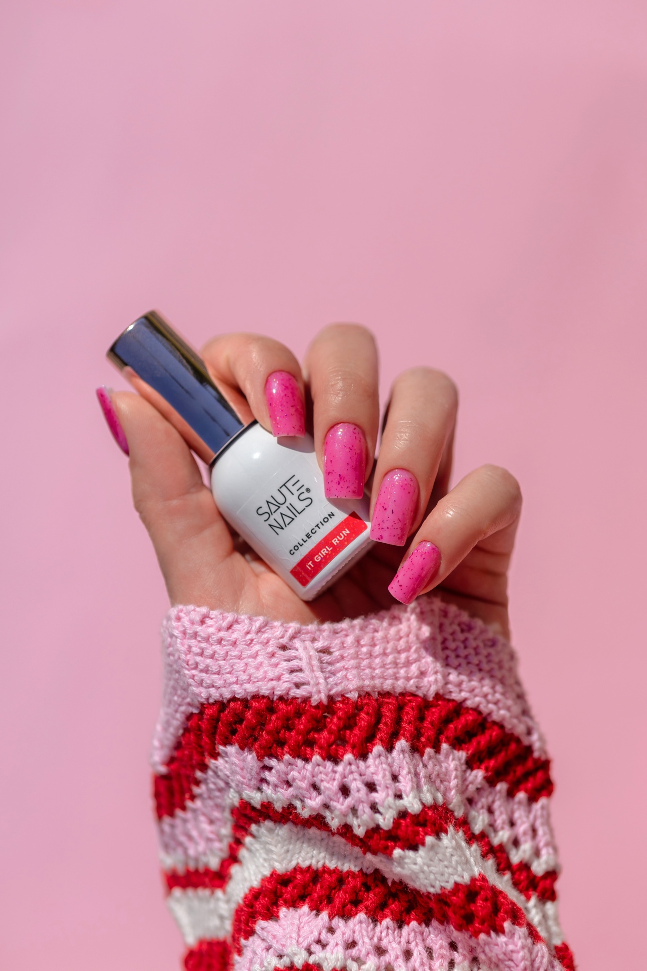 Verniz Gel It Girl Run (Rosa Néon com partículas Rosa Escuro) Unhas pintadas de rosa segurando verniz branco com tampa prateada com texto