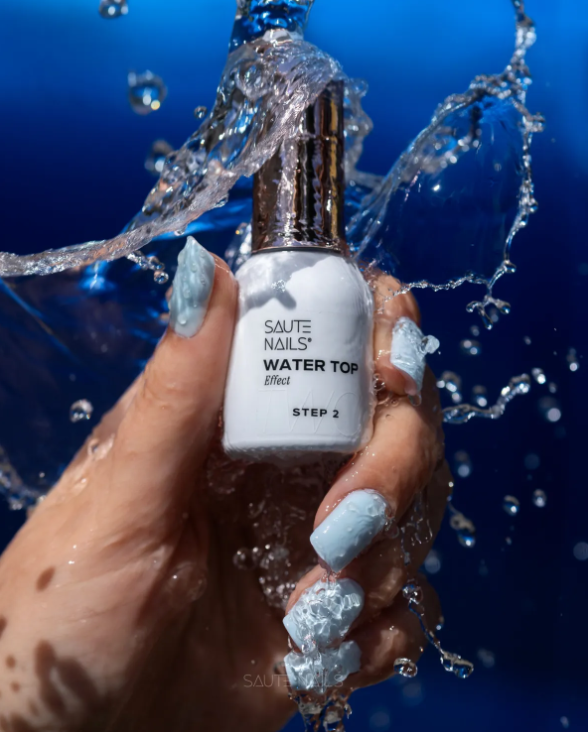 Water Top Saute Nails - Step 1 + Step 2 Frasco de verniz para unhas branco com tampa prateada e mão com unhas azuis molhada por água
