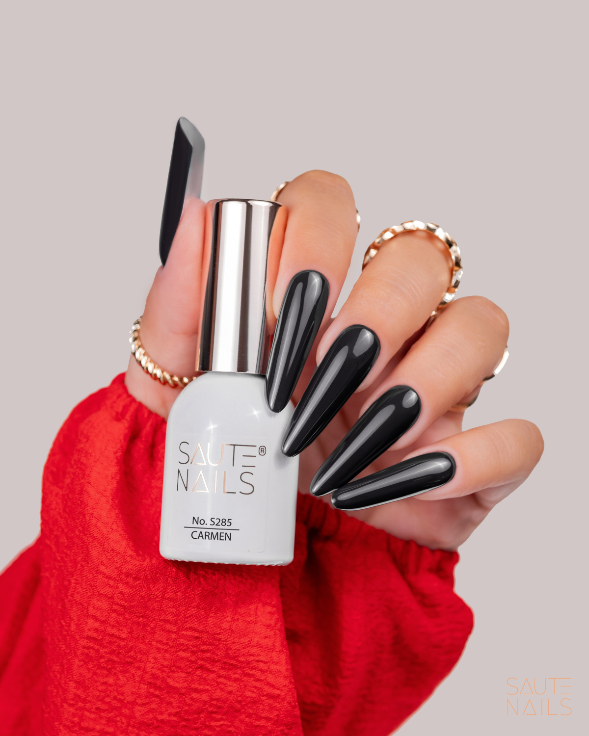 Verniz Gel Saute Nails S285 - Carmen (Preto não puro) Mão com unhas negras brilhantes segurando verniz de unhas SAUTE NAILS no. 5285 CARMEN