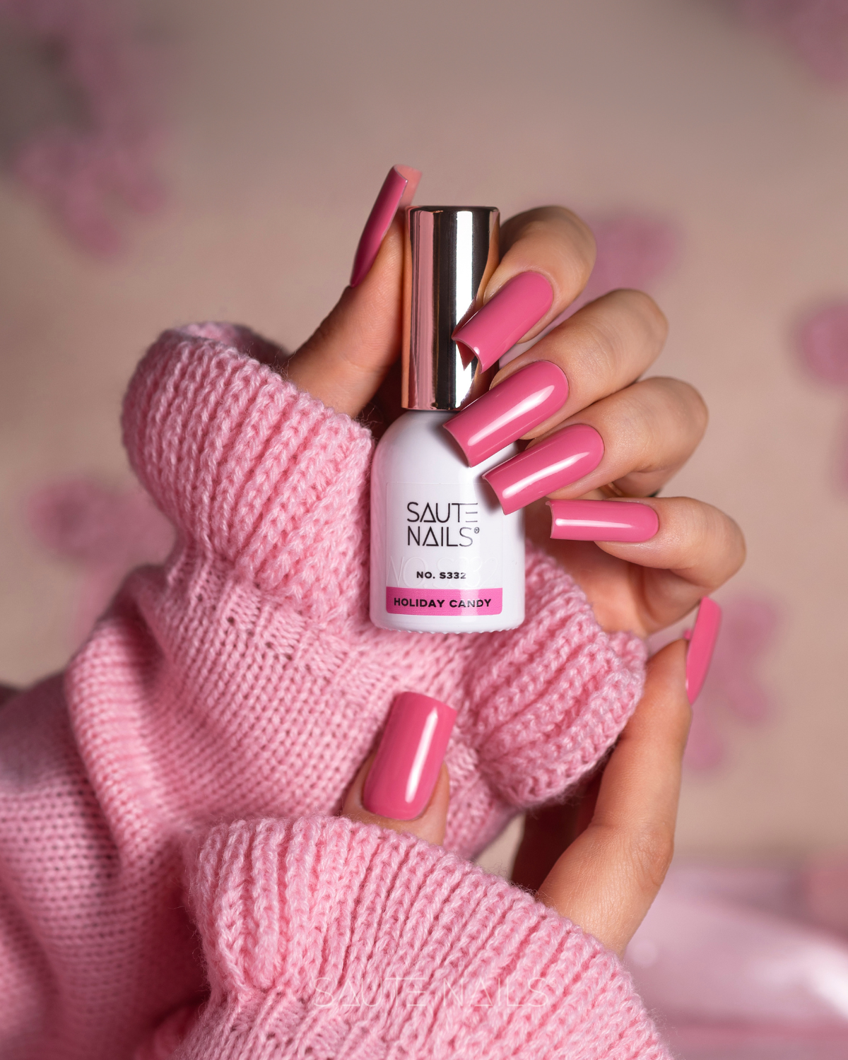 Verniz Gel Saute Nails S332 - Holiday Candy (Rosa Intenso) Mãos com unhas longas rosa seguram frasco de verniz branco e usam camisola rosa
