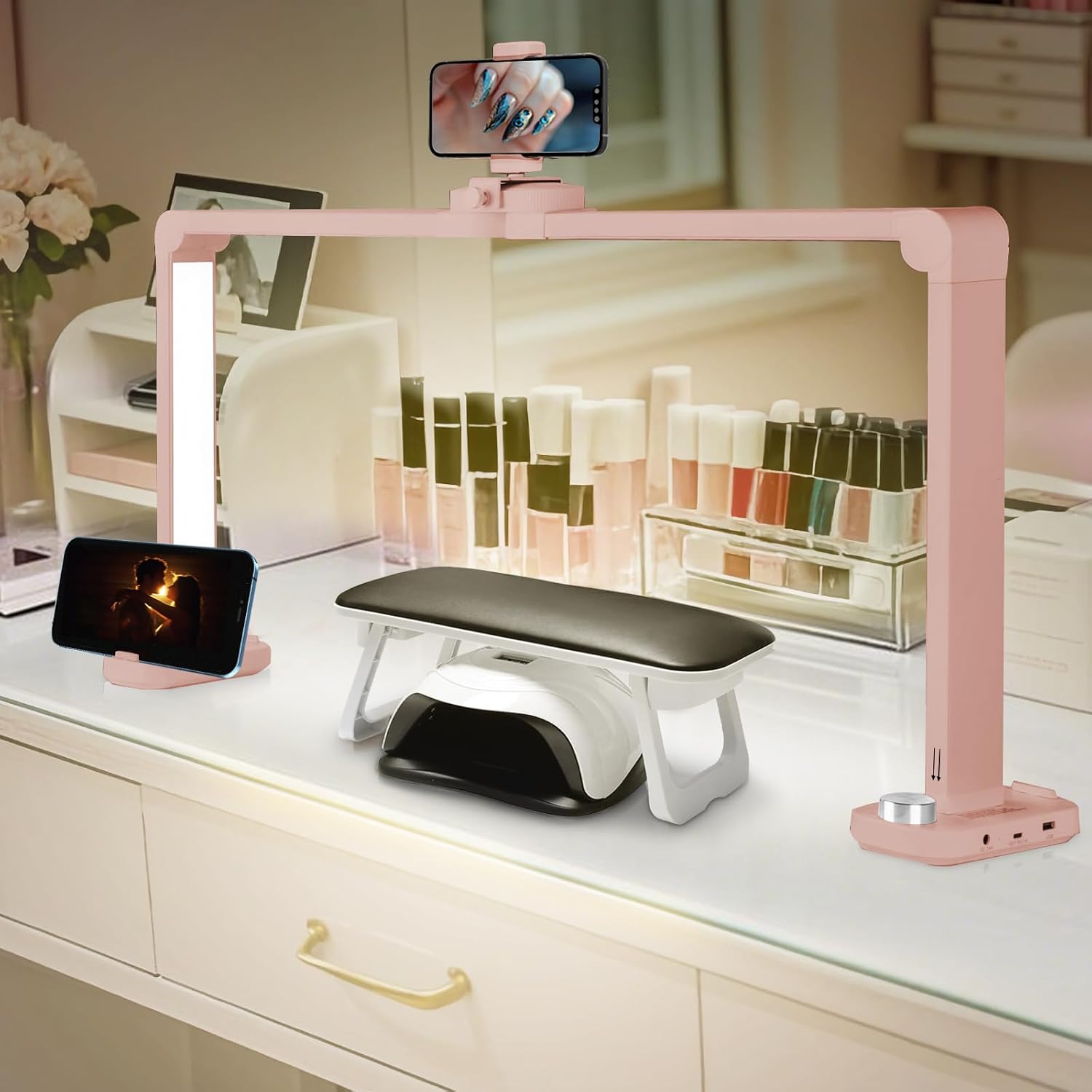 Candeeiro ROSA em Meia Lua 40W para Unhas – LED, 3 Modos com Suporte de Telemóvel Espaço de manicure com luminária rosa, telemóveis em suportes, almofada preta e vernizes em fundo espelhado