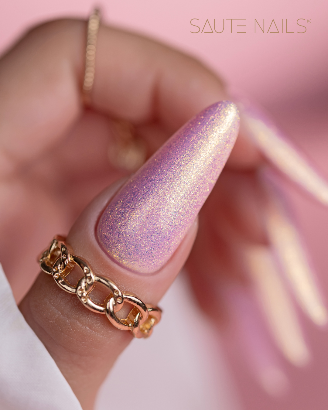 Verniz Gel Saute Nails S277 - Ariel (Partículas Multicolores) Unha artificial rosa cintilante com anel dourado em fundo rosa