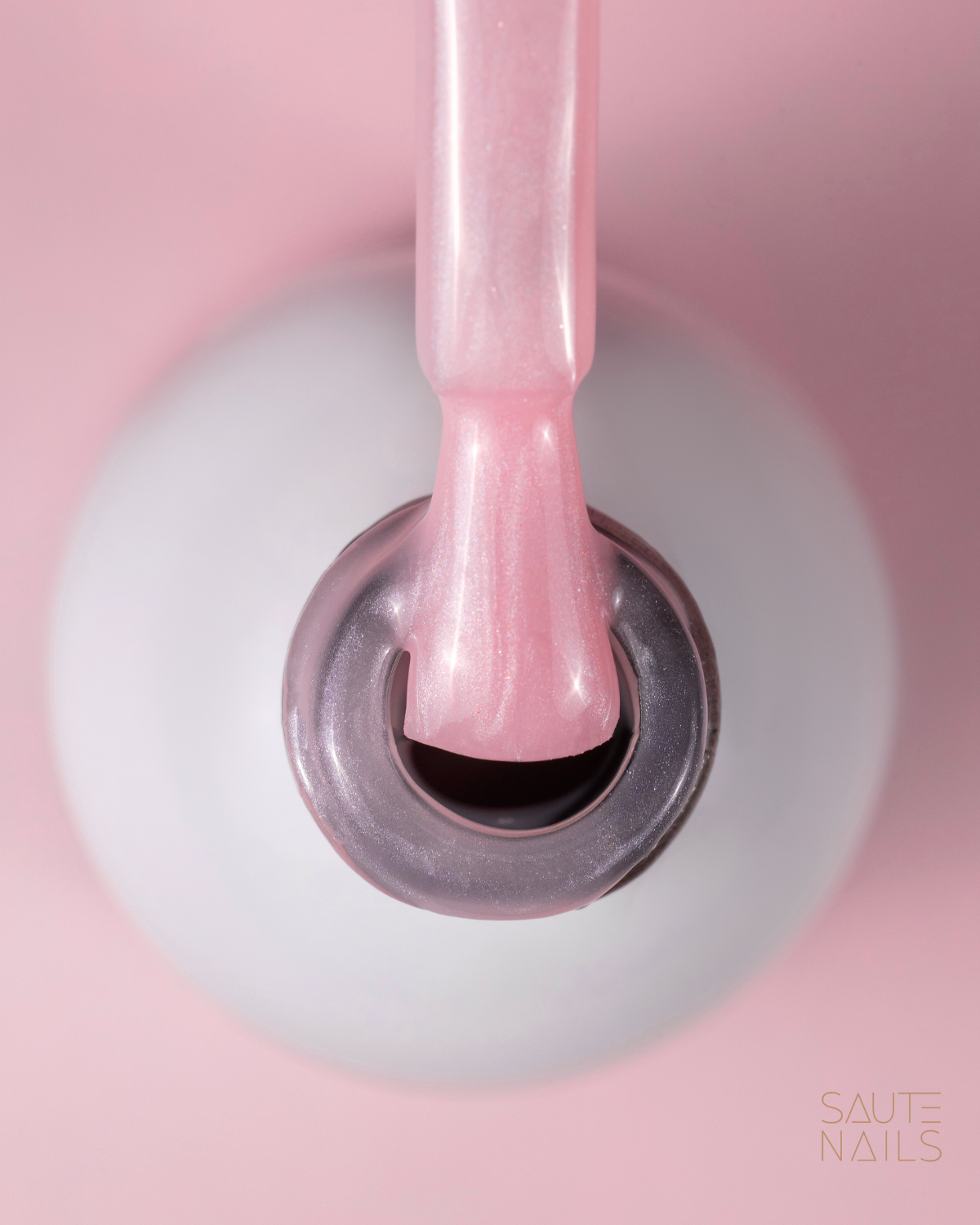 Frasco branco de verniz de unhas com pincel a retirar verniz rosa perolado