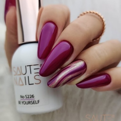 Frasco de verniz de unhas branco e unhas roxas com detalhes dourados.