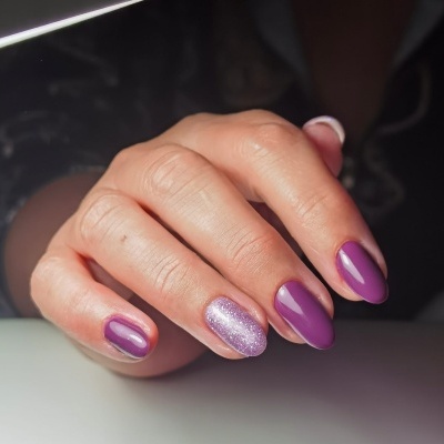 Mão feminina com unhas roxas e uma rosa brilhante.