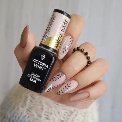 Unhas decoradas com verniz gel nude e desenhos pretos a segurar frasco de verniz Victoria Vynn Mega Base
