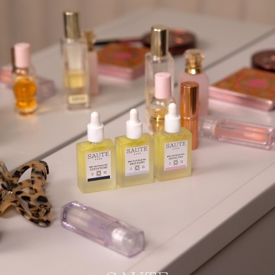 Frascos de óleo para cutículas SAUTE CARE em mesa com produtos de beleza