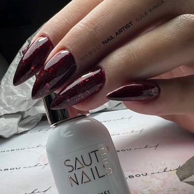 Unhas vinhos escuras brilhantes e frasco de verniz branco Saute Nails