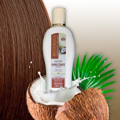 Frasco de condicionador Bio Extratus Óleo de Coco sobre coco partido com leite a salpicar e cabelo castanho ao fundo