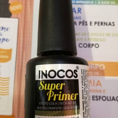 Frasco preto INOCOS Super Primer com rótulo detalhado sobre folheto colorido