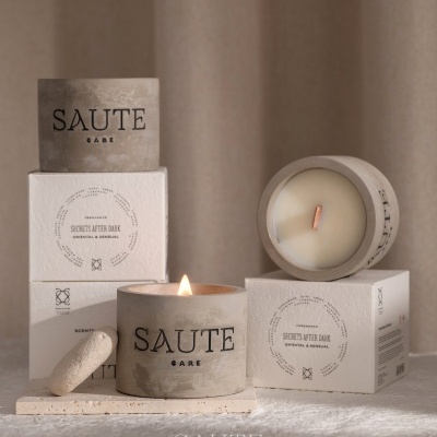 Velas aromáticas SAUTE CARE em recipientes de cimento, com caixa branca e texto Secrets After Dark Oriental & Sensual.