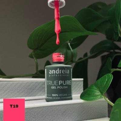 Verniz em gel 'andreia professional' com pincel a pingar verniz coral, sobre caixas brancas com folhas verdes ao fundo