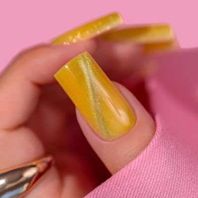 Unha amarelo metálica brilhante em fundo rosa com texto SAUTE NAILS
