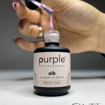 Frasco preto com rótulo branco e mão a aplicar acrígel rosa leitoso