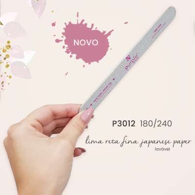 Lima reta fina japonesa de papel cinzenta com texto rosa e preto, segurada por uma mão com unhas pintadas de rosa
