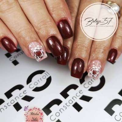 Manicure com verniz castanho escuro e unhas nude com desenhos florais brancos.