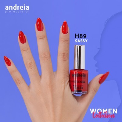 Mão com unhas vermelhas segurando verniz de unhas Andreia H89 Sassy, fundo azul