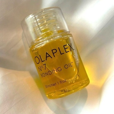 Frasco de óleo amarelo OLAPLEX sobre tecido branco