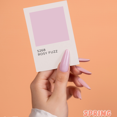 Mão com unhas rosa claro segurando amostra de cor ROSY FUZZ