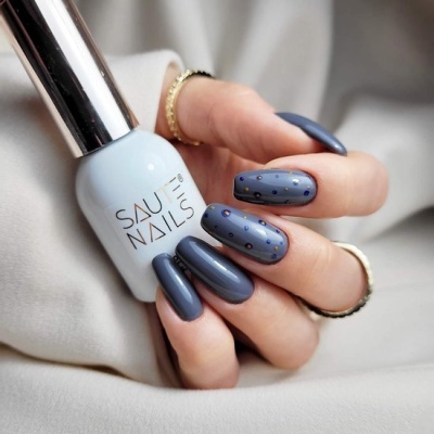 Frasco de verniz de unhas azul claro e unhas pintadas azul escuro com pontos brilhantes