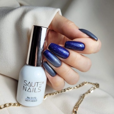 Frasco de verniz de unhas SAUTE NAILS e unhas pintadas em tons de azul com brilho