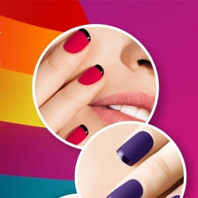 Unhas decoradas com esmaltes foscos em rosa, roxo e preto com detalhes brilhantes e fundo colorido