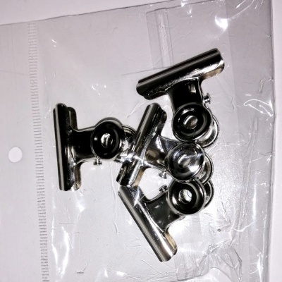 Cinco prendedores metálicos cromados numa embalagem plástica transparente