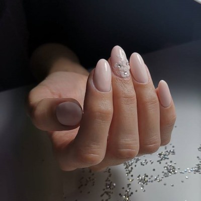 Unhas artificiais rosas claras com decoração de pérolas em fundo claro